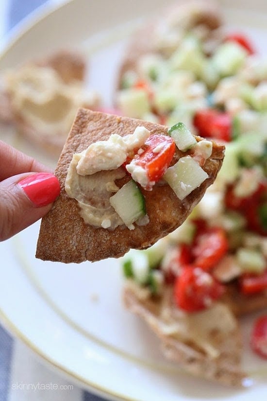 These Greek Nachos are a healthier Greek twist on traditional nachos. They are made with whole wheat pita chips, hummus, cucumbers, tomatoes and feta.