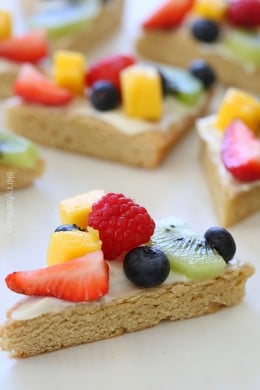 This easy healthy fruit pizza is lightener sugar cookie with white chocolate chips topped with cream cheese frosting and fresh fruit. The perfect rainbow dessert for Mother's Day, Spring or Summer!