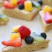 This easy healthy fruit pizza is lightener sugar cookie with white chocolate chips topped with cream cheese frosting and fresh fruit. The perfect rainbow dessert for Mother's Day, Spring or Summer!