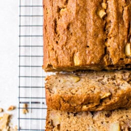 Overhead view of baked apple bread on a wire rack with slices cut from the end.