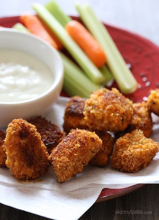 A plate of crispy baked buffalo chicken nuggets with carrots and celery sticks and creamy dipping sauce