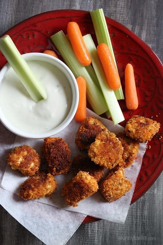 A plate of crispy breaded buffalo chicken nuggets with celery and carrot sticks and creamy dipping sauce.