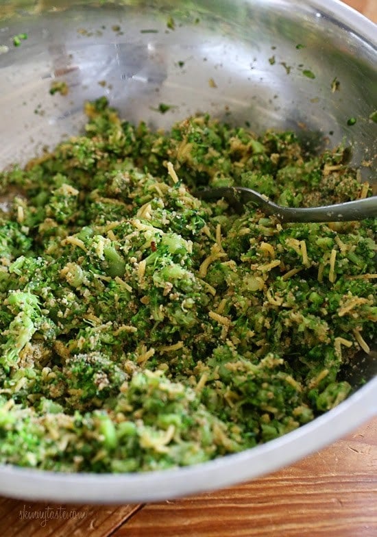 A mixture of chopped broccoli, grated cheese, scallions, and bread crumbs in a mixing bowl
