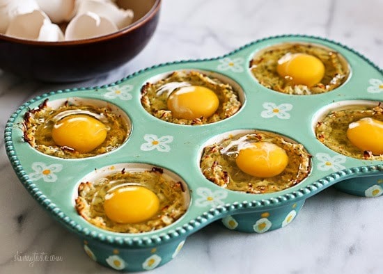 A muffin tin with spaghetti squash mixture and topped with a raw egg in each tin