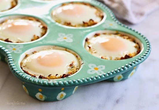 A muffin pan with spaghetti squash mixture and a baked egg in each tin