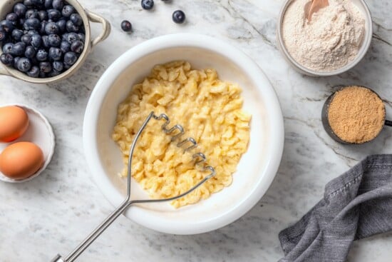 Potato masher in bowl with mashed banana.