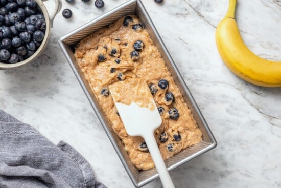 Spreading blueberry banana bread batter into pan.