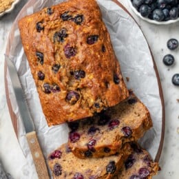 Loaf of blueberry banana bread with 3 slices cut.