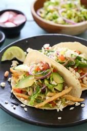 Grilled chicken tacos piled high with a lettuce-tomato slaw, avocado, and Cotija cheese all served on a charred tortilla. A quick weeknight dinner solution!