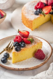 Slice of easy almond cake on plate with fresh berries for garnish