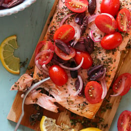 Grilled wild cedar plank salmon with fresh herbs topped with tomatoes, kalamata olives and red onion. This is so flavorful, and simple to make, perfect for weeknight cooking or fancy enough to serve if you're having guests. Aside from soaking the plank in water, the rest takes under 30 minutes to make.