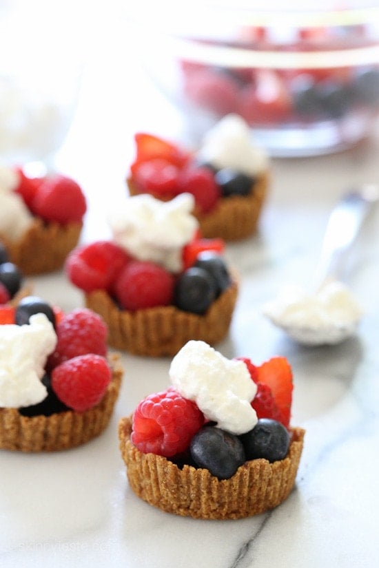 Perfect summer treat, these tartlets are made with a graham cracker crust, drizzled with dark chocolate and filled with fresh berries