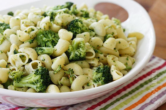 A bowl of short tube shaped pasta mixed with broccoli florets.