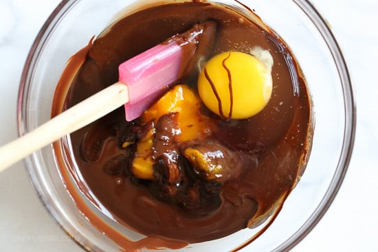 Eggs and pumpkin being stirred into melted chocolate