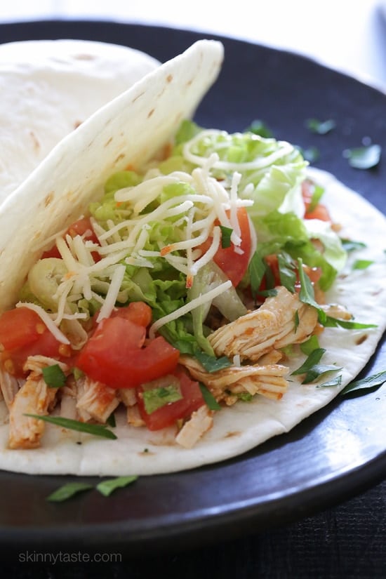 Instant Pot salsa chicken served in a flour tortilla with taco toppings.