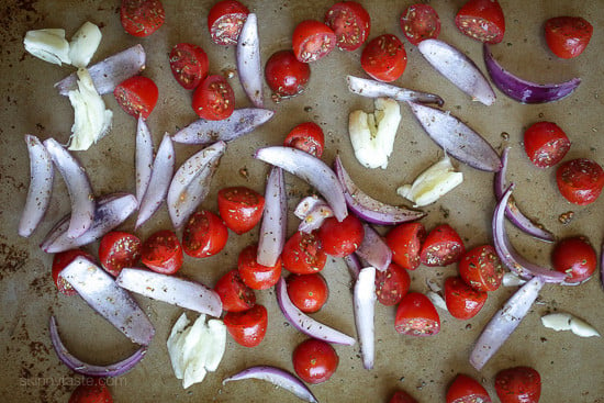garlic, red inions and tomatoes on a sheet pan.
