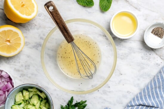 Lemon dressing in bowl with small whisk.