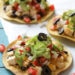 These easy loaded chicken "nacho" tostadas – topped with cheese, tomatoes, guacamole, olives and jalapenos are a great way to take nachos and turn them into a main dish.