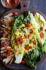 An EASY 15-minute dish you'll want to make all summer long! Fresh heads of romaine lettuce are split down the middle, grilled until slightly charred and smoky, along with fresh corn and skinless chicken thighs, then topped with tomatoes, onions, avocado and a simple salsa vinaigrette.