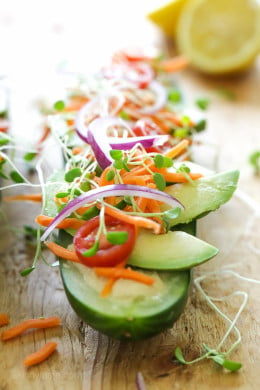 Cucumbers with the seeds scooped out and filled with hummus, avocado, tomatoes, onion and sprouts. So refreshing, healthy and light! An easy low-carb, low-sodium, gluten-free alternative to bread.
