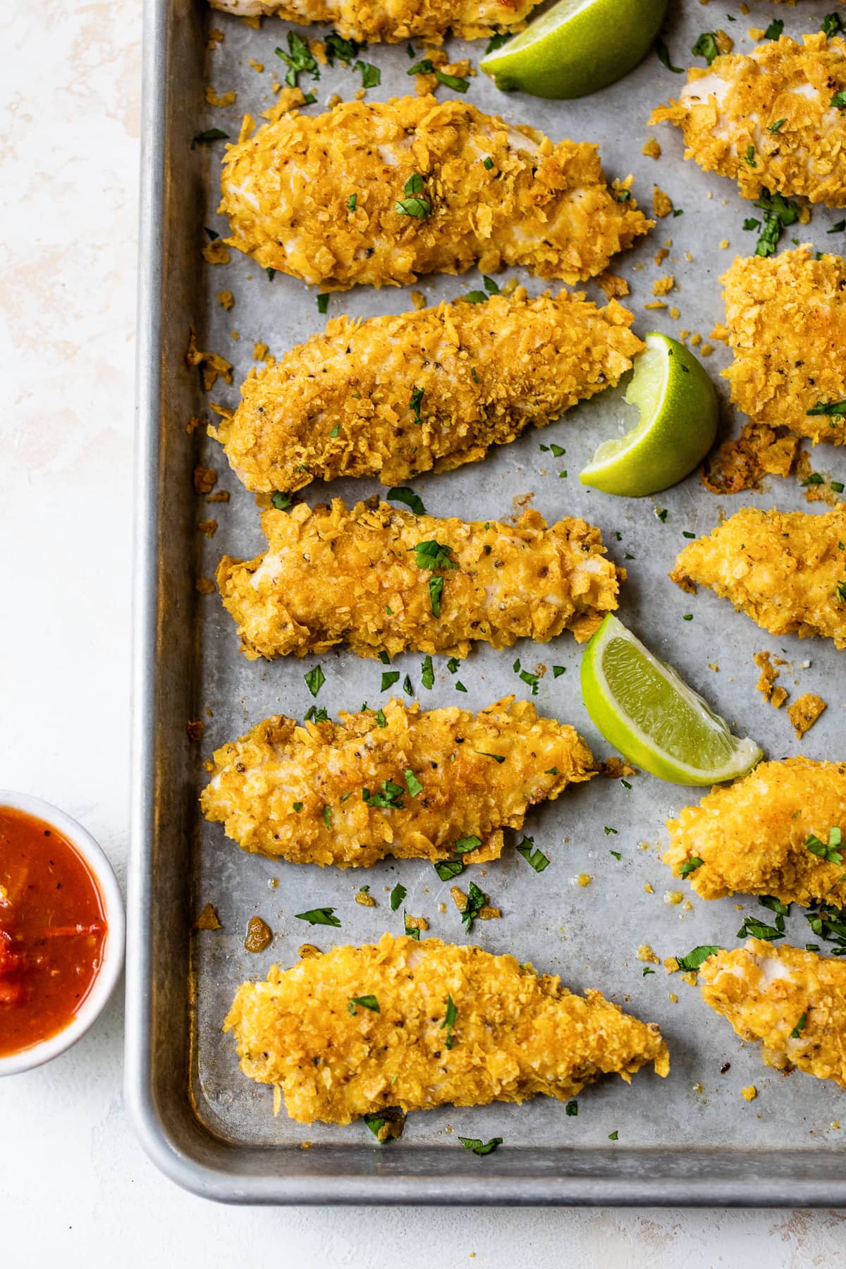 Tortilla-crusted chicken tenders with lime wedges