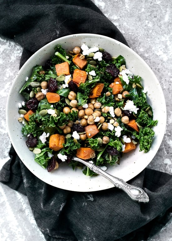 A beautiful salad made with massaged kale, roasted sweet potatoes, dried cherries, crumbled Feta cheese and pepitas. An easy kale and sweet potato recipe that's nourishing and delicious!