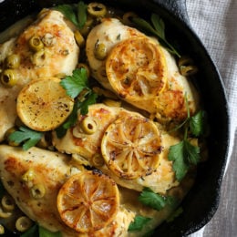 Chicken breasts cooked in a skillet with green olives, lemon and fresh herbs.