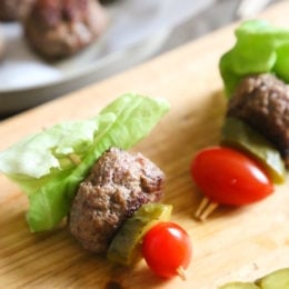 Mini burgers with bacon, layered on a bamboo skewer with lettuce, tomatoes and pickles! Who can resist your favorite foods on a stick – not me! These burger bites make the perfect low-carb appetizer to please everyone from age six to age sixty, just set out some ketchup and mustard for dipping and watch them disappear.