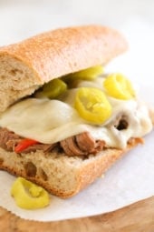 Set it and forget it with this easy slow cooker sandwich recipe. Top round roast, bell peppers, pepperoncini, garlic and dried herbs slow cooked all day then shredded and served on whole wheat Italian bread or rolls with melted provolone.