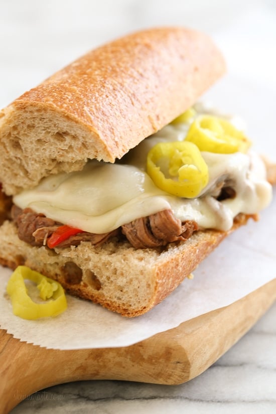 Set it and forget it with this easy slow cooker sandwich recipe! Made with a beef roast, bell peppers, pepperoncini, garlic and dried herbs, served on whole wheat Italian bread or rolls with melted provolone.