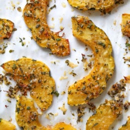 Roasted Delicata squash is delicious topped with a Parmesan-herb crust. The edges come out crisp, golden and delicious. Whether you serve it as a healthy snack or a side dish, this roasted delicata squash recipe is always a winner!