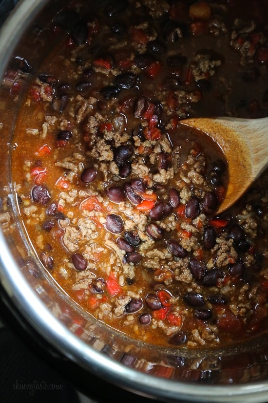 A wooden spoon stirring beef chili