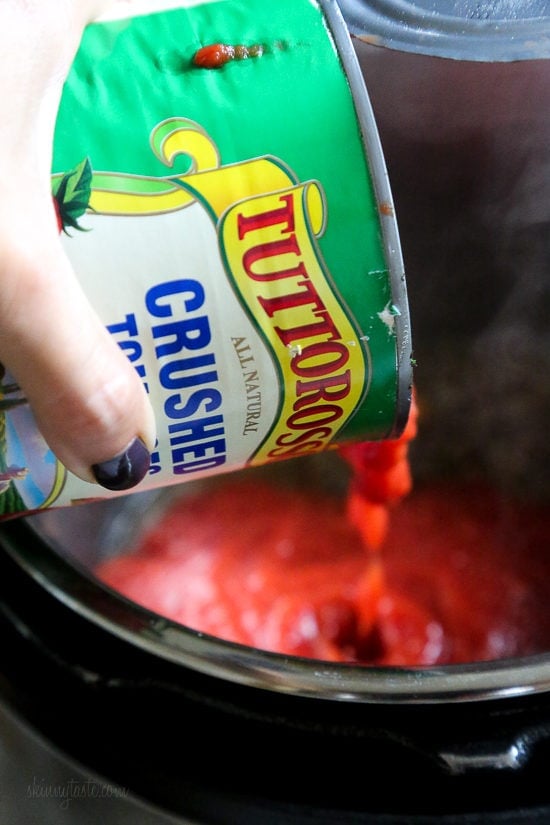 A can of crushed tomatoes is poured into the Instant Pot.