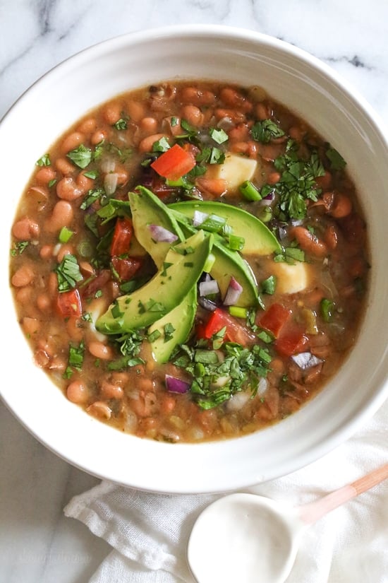 Mexican Pinto Beans, Frijoles Con Todo are made from scratch in the pressure cooker with dry pinto beans, onions, chile, jalapeno, tomatoes, cilantro, avocado and my favorite part, the queso! These soupy beans are not spicy, and can be served as a soup or as a side dish over rice or with tortillas.