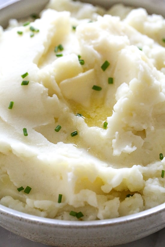 Close up of a bowl of creamy Instant Pot mashed potatoes topped with chopped chives.