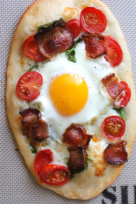This easy, homemade breakfast pizza is made with bacon, eggs, tomatoes, spinach and cheese, made completely from scratch and ready in less than 30 minutes start to finish!