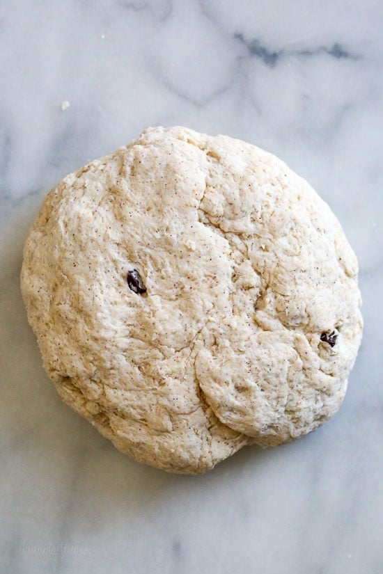 Make soft homemade hot cross buns without yeast, filled with spice, raisins, and finished with icing. Easy to bake in the oven or air fryer! Overhead view of homemade hot cross bun dough on a countertop.