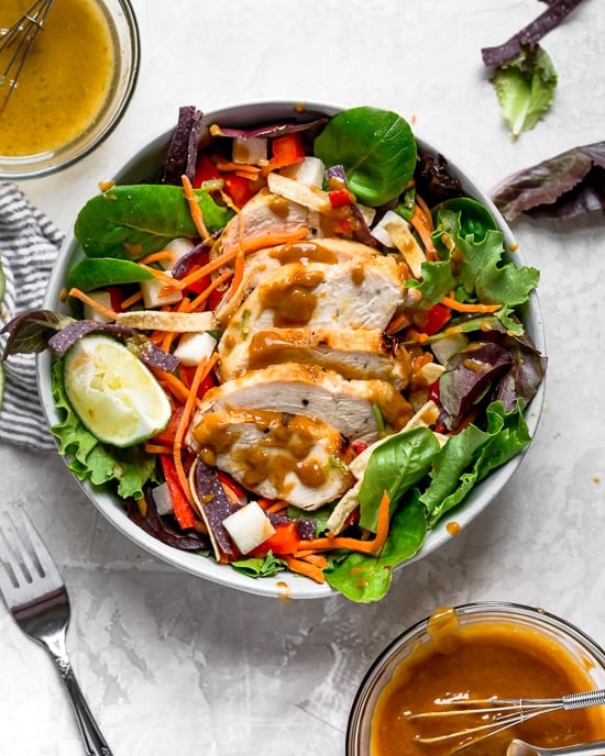 Grilled Chicken Salad with greens and vegetables are tossed in a honey-lime vinaigrette and topped with a delicious peanut sauce.