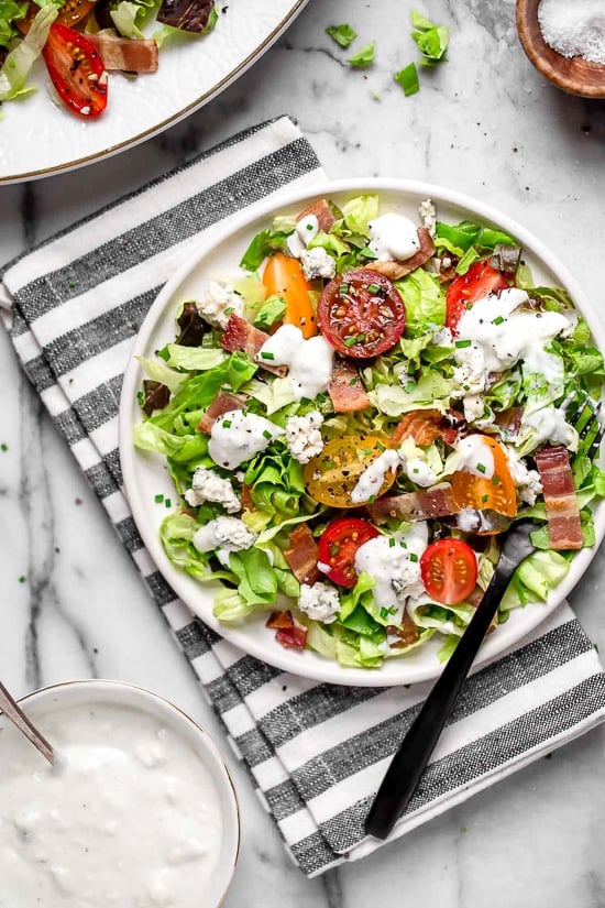Classic wedge salad meets chopped salad in this easy side salad dish made with lettuce, bacon, blue cheese and chives with a light homemade blue cheese dressing.