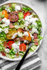 Classic wedge salad meets chopped salad in this easy side salad dish made with lettuce, bacon, tomatoes, blue cheese and chives with a light homemade blue cheese dressing.
