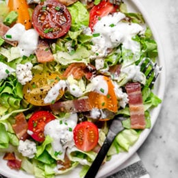 Classic wedge salad meets chopped salad in this easy side salad dish made with lettuce, bacon, tomatoes, blue cheese and chives with a light homemade blue cheese dressing.