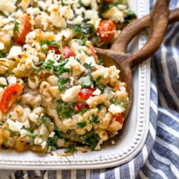 Greek Mac and Cheese, a healthy twist on a comfort food classic made in a creamy cheese sauce with whole wheat pasta, tomatoes, spinach, olives and Feta cheese.
