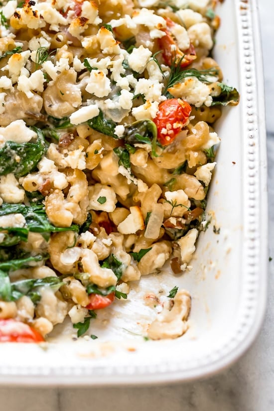 Greek Mac and Cheese, a healthy twist on a comfort food classic made in a creamy cheese sauce with whole wheat pasta, tomatoes, spinach, olives and Feta cheese.