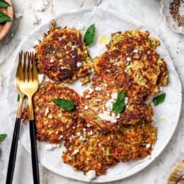 Plate of zucchini fritters with feta and mint.