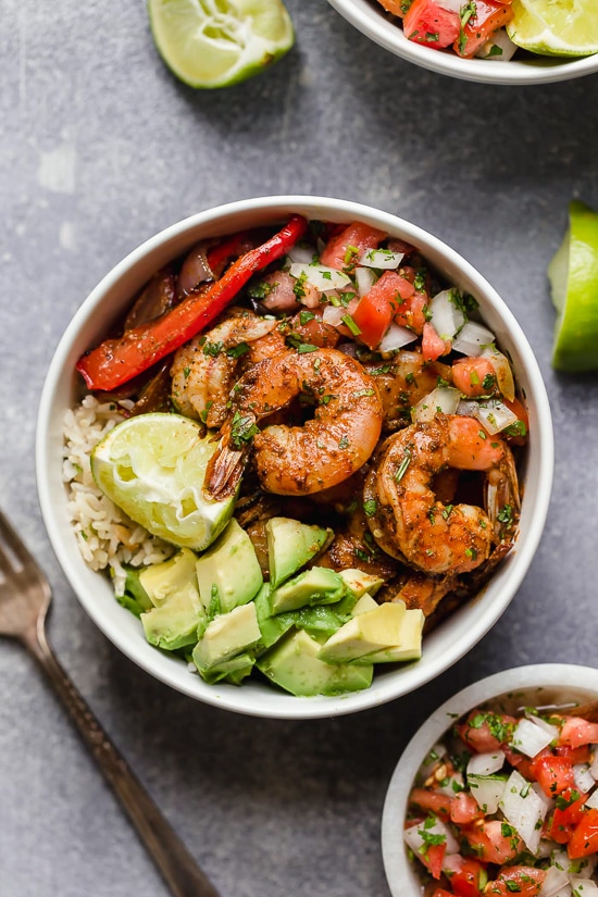 These Shrimp Fajita Bowls are a tasty and easy dinner that your whole family will love! Served over a bed of cilantro-lime rice with peppers and onions, avocado and salsa.