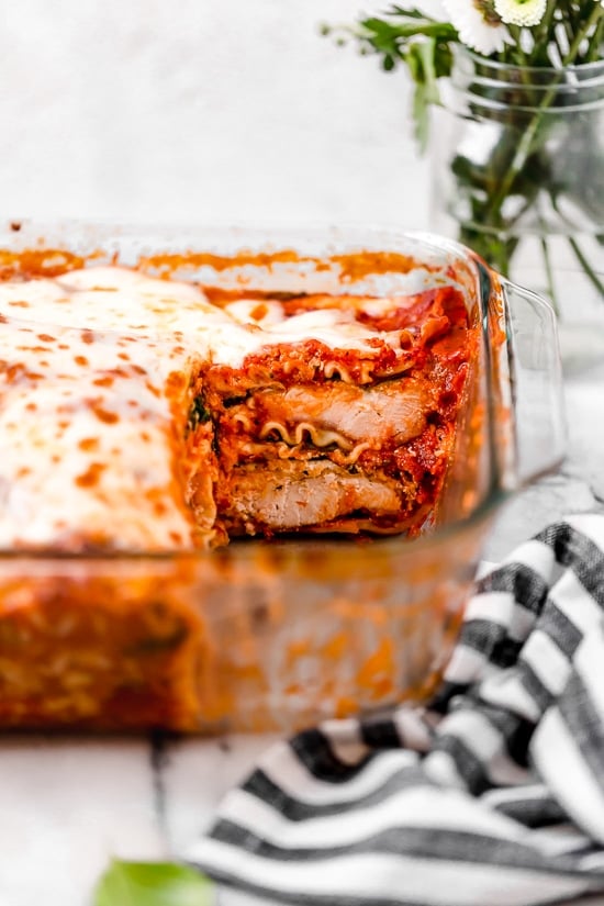 A casserole of chicken parmesan lasagna with a piece missing