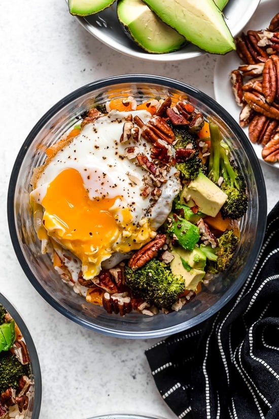 This easy Buddha Bowl is made with roasted broccoli, butternut squash, and onions piled on top of whole grain rice and topped with sliced avocado, a sunny-side fried egg, and crunchy pecans.