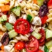 Greek Pasta Salad is light and fresh, loaded with garden tomatoes, bell peppers and cucumbers tossed in a homemade Greek dressing with Kalamata olives and Feta cheese. Perfect for summer parties!