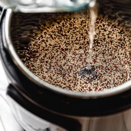 Water is added to an Instant Pot filled with uncooked quinoa.