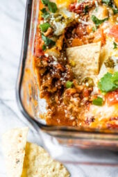 Grab some chips and dig into this cheesy, hot Mexican Layer Dip made with spiced ground turkey, refried beans, salsa, green chilies, tomatoes, cheese and avocado.